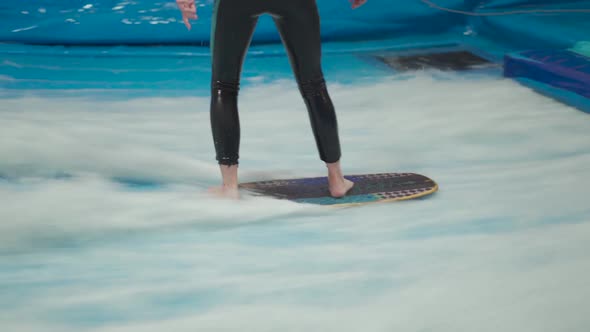 Teenager is Riding Surf Board on Wave Simulator Indoors