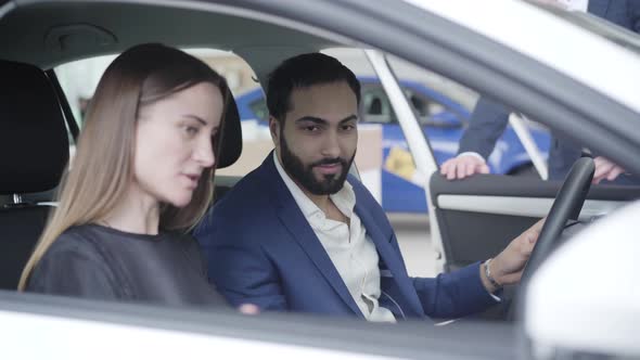 Portrait of Handsome Middle Eastern Man Sitting in Car with Caucasian Wife As Trader Closing Doors