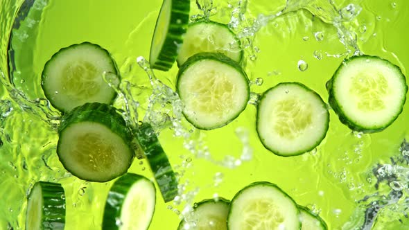 Super Slow Motion Shot of Cucumber Slices Falling Into Water on Green Background at 1000Fps.