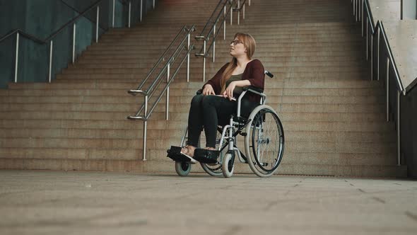 Hopeless Young Woman in the Wheelchair in Front of the Inaccessible Stairs.