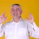 Elderly gray-haired man look at camera with crossed fingers wish isolated on yellow background - VideoHive Item for Sale