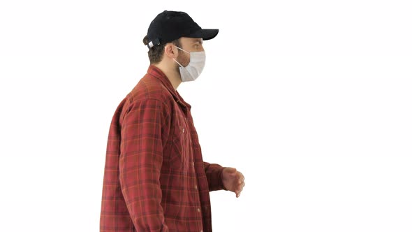 American Farmer in a Cap and Medical Mask Walks Along on White Background