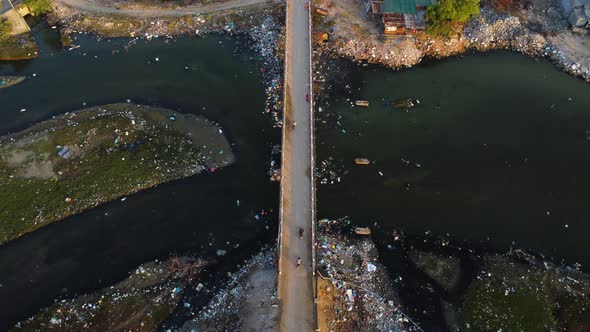 Aerial birdseye static shot of bridge over polluted river, Vietnam