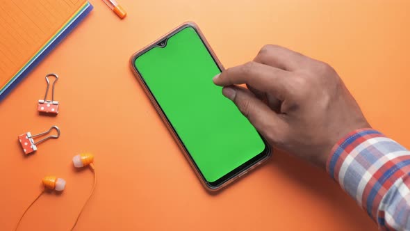 Man's Hand Using Smart Phone on Orange Background 