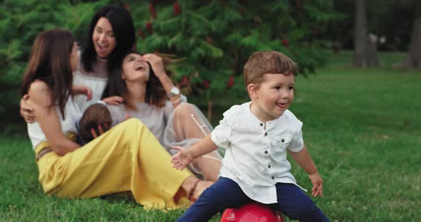 Funny Little Boy Sitting on a Red Ball Background