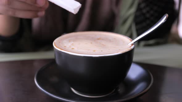 Person Hand Stirring Coffee with Spoon.