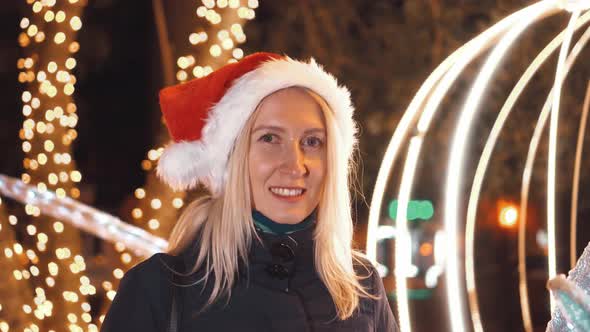 Portrait of a woman smiling at the camera and playing in a Santa hat