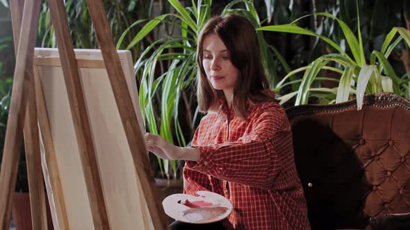 Artist in an Art Studio with Plants  Young Pretty Woman Drawing a Painting with Colors