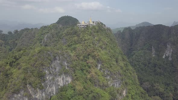 Aerial footage of Buddha on top of Tiger Cave Temple, Wat Thum Sua, stone rocks, Krabi, Thailand.