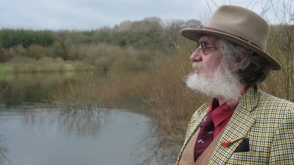 An elderly man looking out over the lake sadly