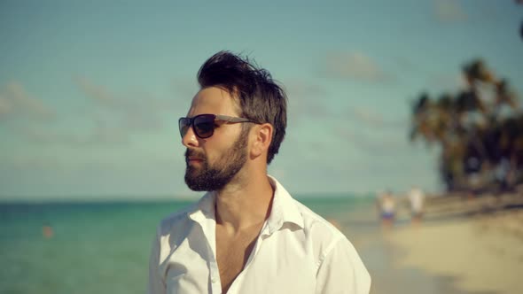 Businessman Walking On Tropical Beach. Man In White Shirt Walks Along Beach On Tropical Beach.