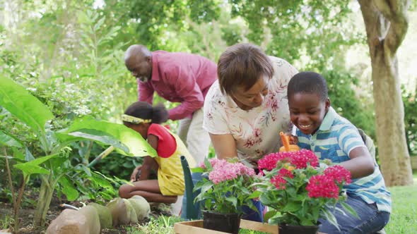 Animation of happy african american grandmother and grandson planting flowers in garden