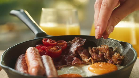 Pouring Spice Red Pepper on Fried Eggs in Pan