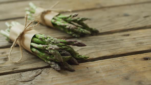 Video of two fresh asparagus bundles with copy space on wooden background