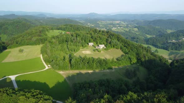 Cinematic view of the drone flying over the green hill. Settlement over the green forest hill.