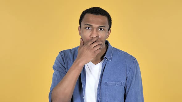 Surprised Young African Man in Shock Yellow Background Wondering