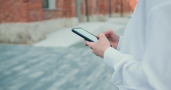 Woman Hands Using Smartphone on City Street Background.