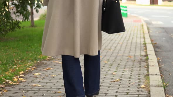 An Elderly Woman Strolls Down a Sidewalk in an Urban Area