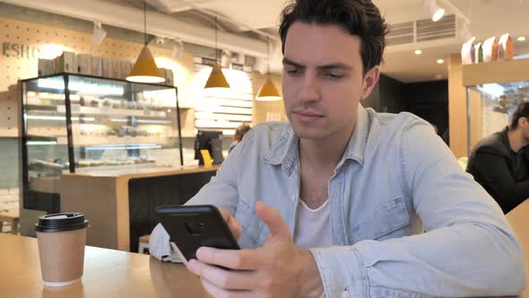 Young Man in Cafe Shopping Online on Smartphone Payment