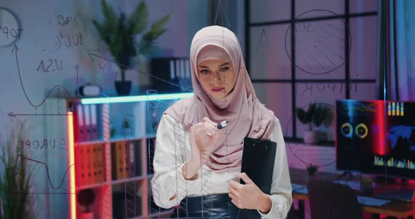 Arabian Female Office Manager in Hijab which Drawing on Transparent wall with Marker