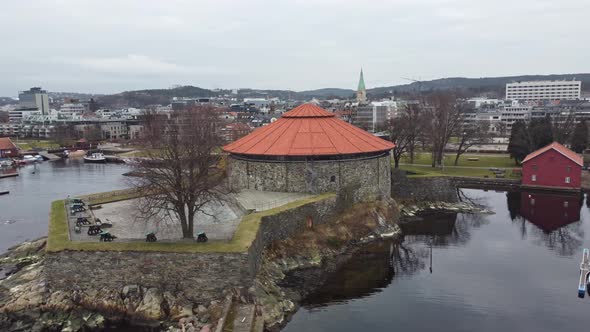 Aerial slowly rotating around front of Kristiansand fortress during cloudy morning - Norway