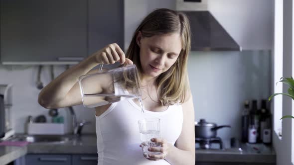 Calm Beautiful Woman Pouring and Drinking Water