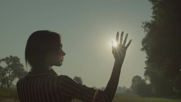 Glare of Rising Sun Through Female Fingers Outdoors
