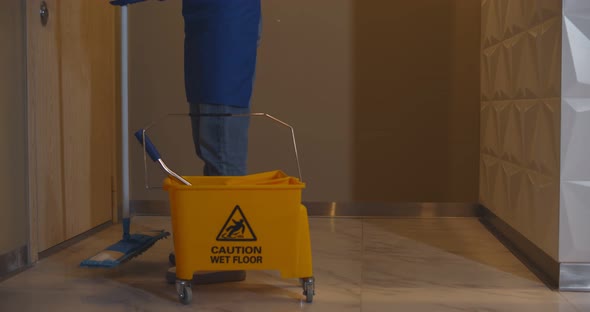 Close Up of Janitor with Bucket of Detergents and Sprays Opening Door of Apartment