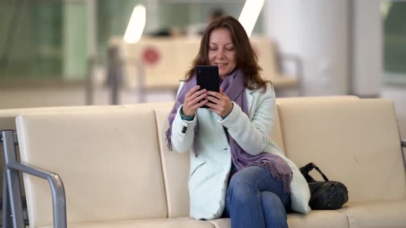Woman Is Waiting Boarding in Terminal of International Airport, Using Smartphone with Free Wifi