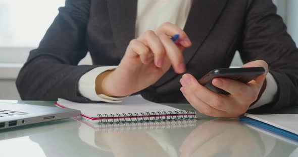 Female Hands in the Office with a Cell Phone in the Office She Increases the Data in the Smartphone