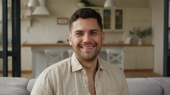 Handsome, positive adult man sitting on the couch in the apartment