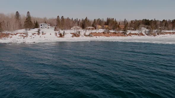 Flying Over Lake Superior With Snowy Lakefront Houses In The Distance In Duluth, Minnesota. - aerial