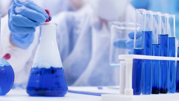 Close Up of Scientist Taking Multiple Samples From a Smoking Blue Fluid Using a Pipette alt