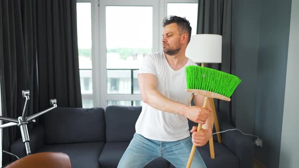 Man Cleaning the House and Having Fun Dancing with a Broom