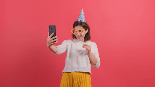 Happy Young Woman in Party Hat Holding Birthday Accessories on Red Background