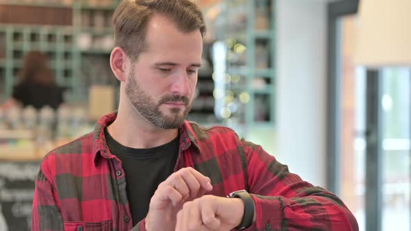 Portrait of Serious Young Man Using Smart Watch