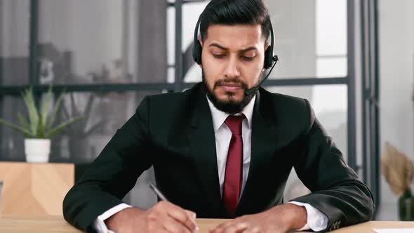 Photo of Successful Serious Indian or Arabian Young Businessman Financial Mentor with Headset Sit at