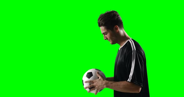 Football player holding a football against green screen