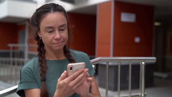 Close-up of a Woman Scrolling and Tapping on a Smartphone Against the Background of a Modern