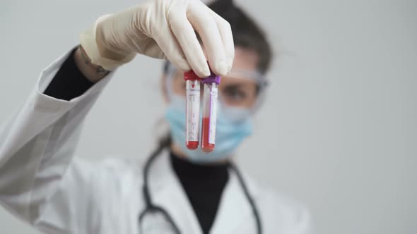 Female Doctor in White Coat Holding Test Tubes with Blood for Coronavirus Tests