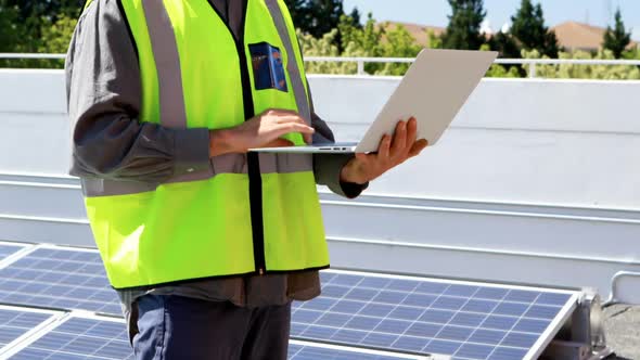 Male worker using laptop at solar station