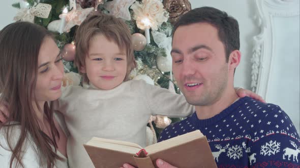 Happy Family of Three Reading Together on Christmas Evening