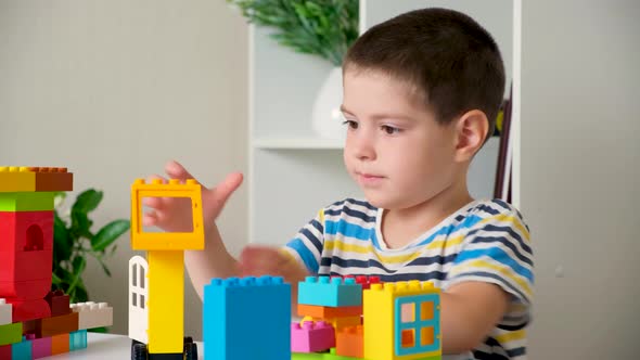 A Boy of 5 Years Old Plays As a Constructor Builds From Multicolored Cubes