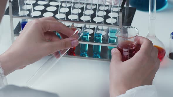 Doctor Pouring Red Solution Into Flask and Putting Into Stand alt
