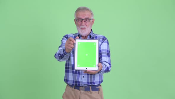 Happy Senior Bearded Hipster Man Showing Digital Tablet and Looking Surprised