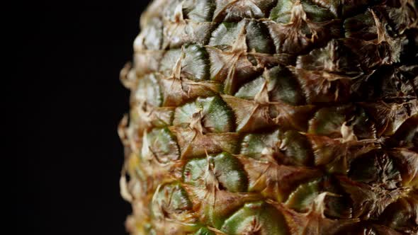 Detailed macro shot of rotating pineapple fruit isolated on black background