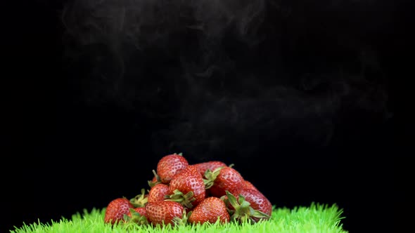 White smoke covering pile of red strawberries against black background