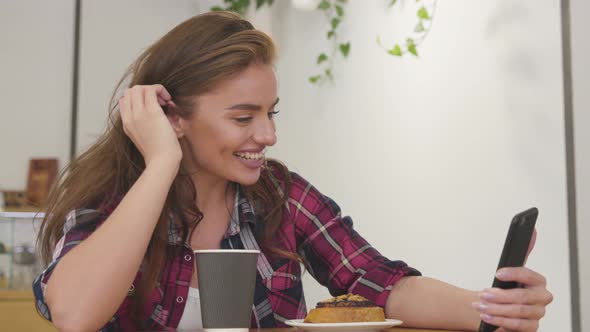 Woman with phone making video call and drinking coffee in cafe. 