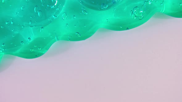 Transparent Green Gel Fluid with Bubbles Flowing Down on a White Surface