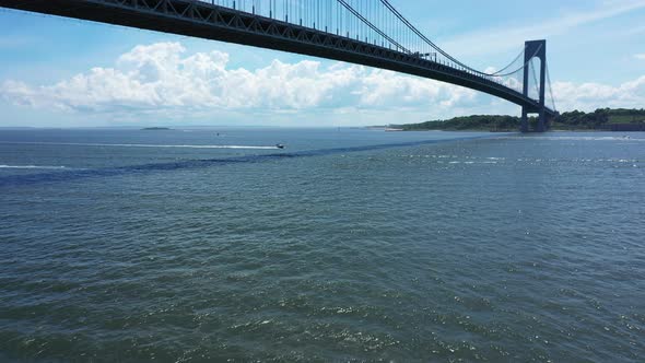 a low angle drone view of Lower New York Bay. The drone dolly in & pan right below The Verazzano Bri